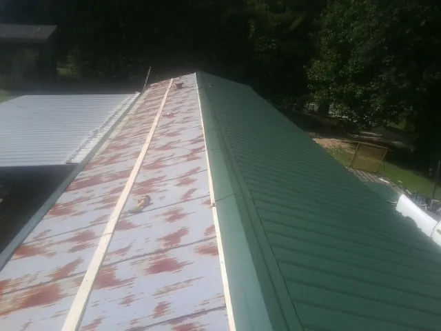 Old rusted panels beside newly installed green metal roofing — Wind Damage Roof Repair by Roofing Brothers in Jerseyville