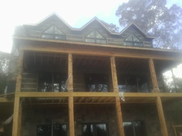 Dormers and porch framing on a large log home under construction — Roof Coating work by our crew in Jerseyville