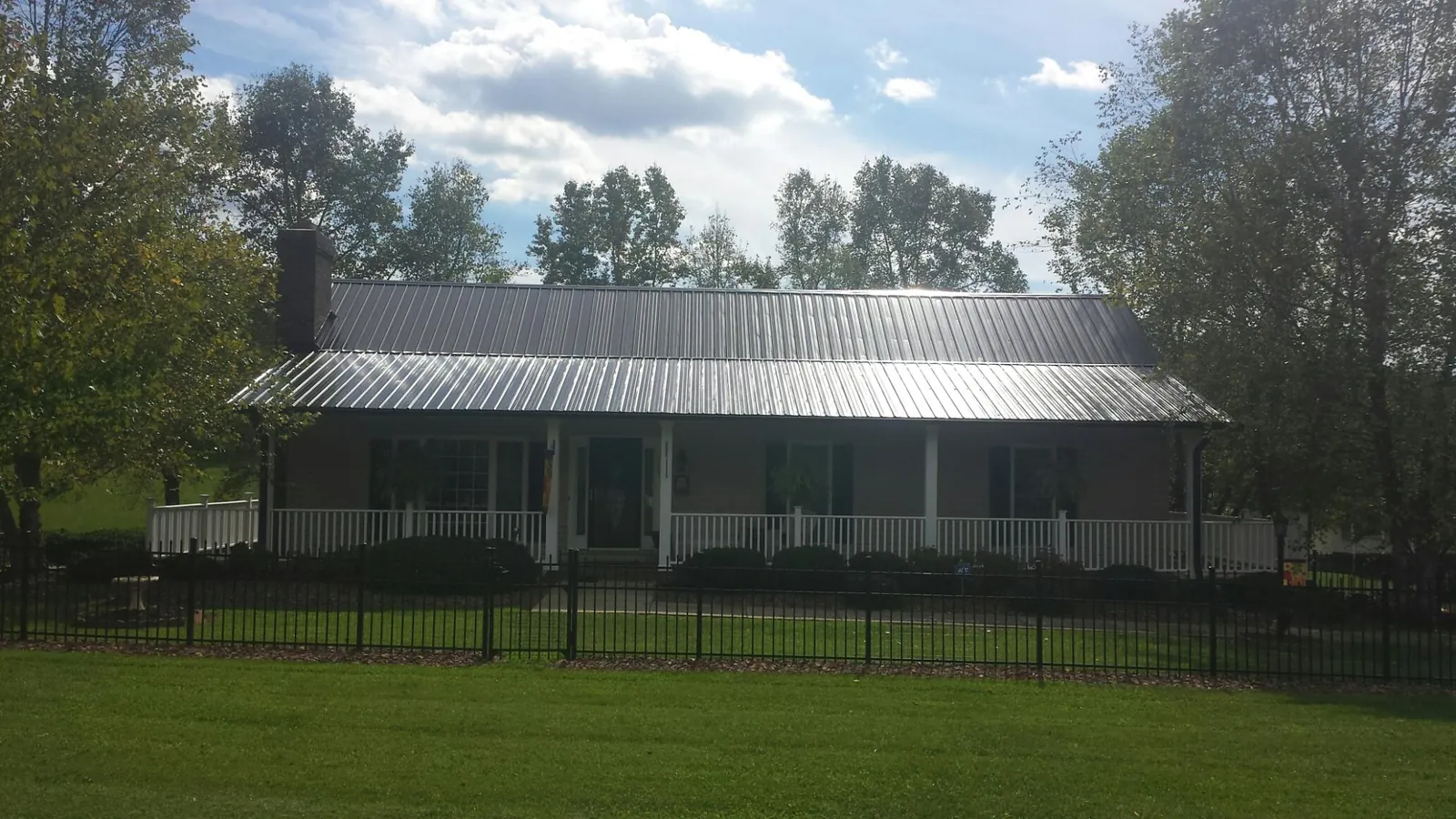 Gray metal roof on a brick ranch with a full width front porch — Gutter Guard Installation work by our crew in Jerseyville