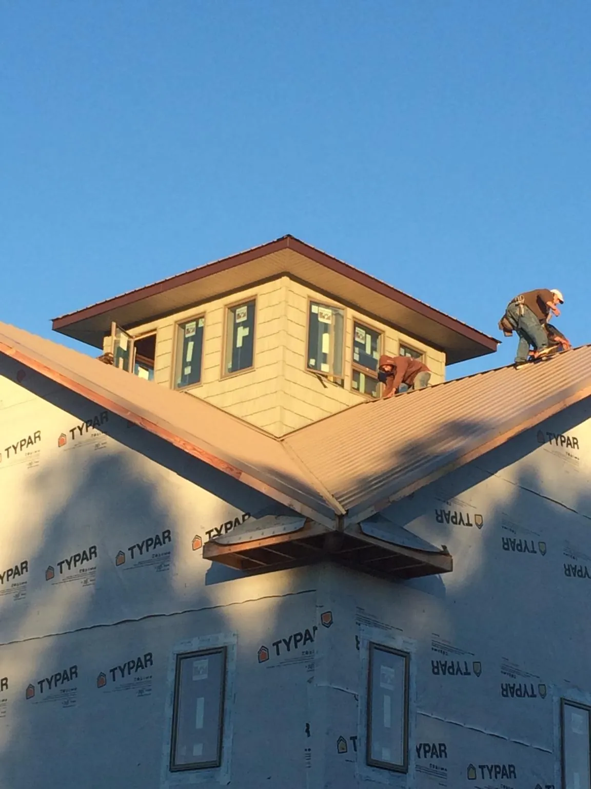 Roofers working around a rooftop cupola on a new metal roof at sunset — Roof Waterproofing in Jerseyville by Roofing Brothers